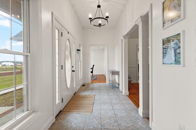 interior space with light hardwood / wood-style floors, ornate columns, a chandelier, and plenty of natural light