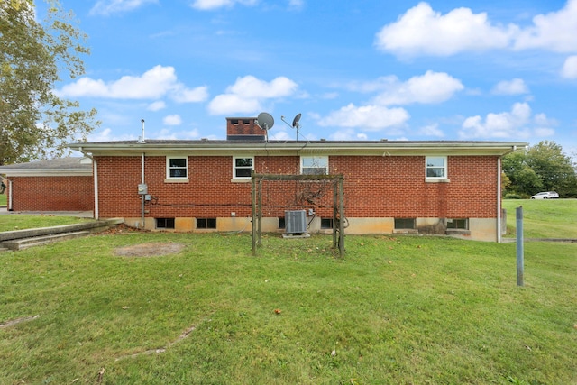 back of house featuring central air condition unit and a lawn