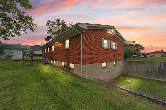 property exterior at dusk featuring a lawn and central AC unit