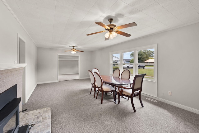 carpeted dining room with ceiling fan and a brick fireplace