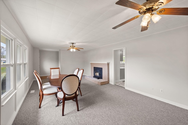 carpeted dining room featuring a brick fireplace and ceiling fan