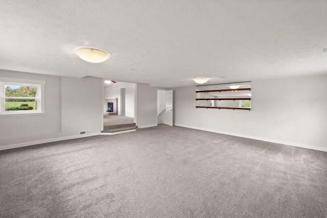 unfurnished room with carpet floors, a textured ceiling, and a fireplace