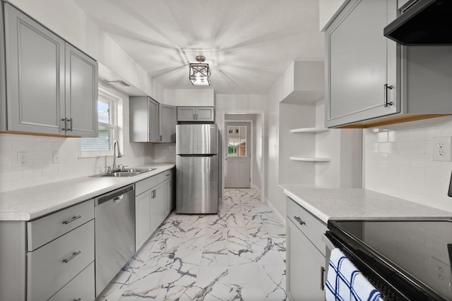 kitchen featuring appliances with stainless steel finishes, tasteful backsplash, sink, and gray cabinetry