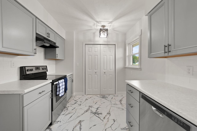 kitchen with gray cabinetry, stainless steel appliances, and backsplash