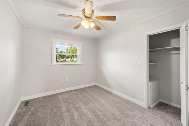 unfurnished bedroom with a closet, ornamental molding, carpet flooring, and ceiling fan