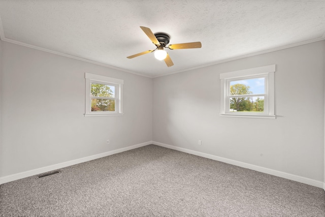 carpeted empty room featuring ceiling fan, ornamental molding, a textured ceiling, and plenty of natural light