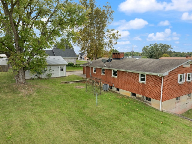 rear view of house featuring central AC and a yard