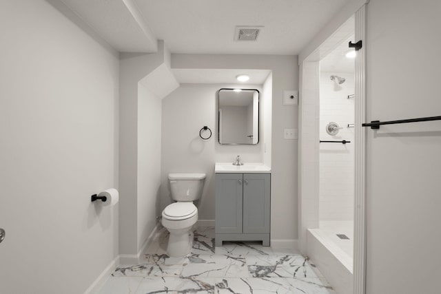 bathroom featuring vanity, toilet, and a tile shower