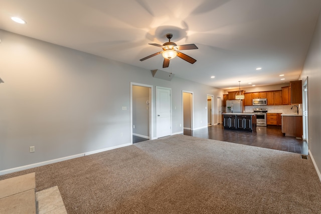 unfurnished living room with ceiling fan, sink, and dark colored carpet