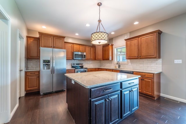 kitchen with a kitchen island, light stone countertops, stainless steel appliances, dark wood-type flooring, and decorative light fixtures