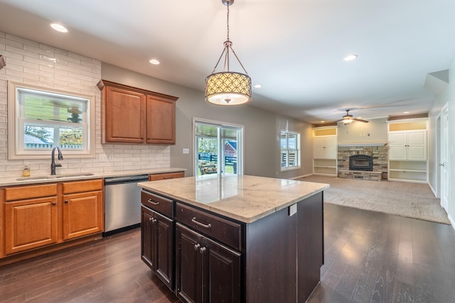 kitchen featuring stainless steel dishwasher, sink, dark wood-type flooring, and a stone fireplace