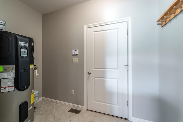 laundry room featuring water heater and light tile patterned floors