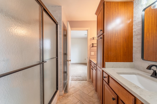 bathroom featuring vanity, decorative backsplash, and a shower with shower door