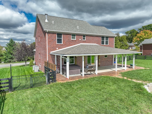 back of property featuring a yard, a patio, and a hot tub