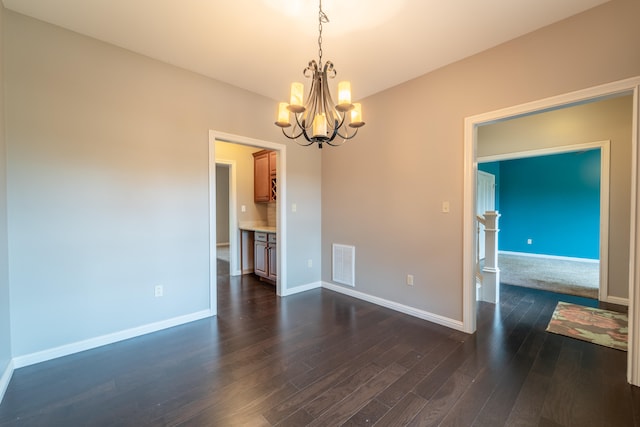 empty room featuring an inviting chandelier and dark hardwood / wood-style floors