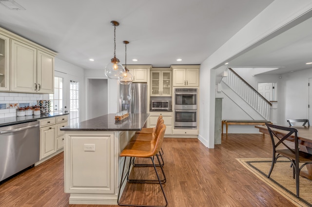 kitchen with pendant lighting, appliances with stainless steel finishes, a center island, and cream cabinetry