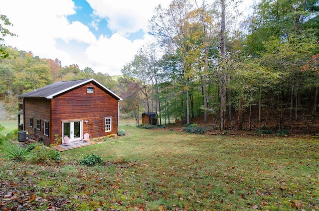 view of yard featuring french doors, a view of trees, and central AC