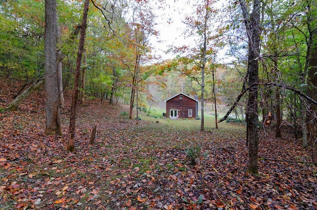 view of yard with an outdoor structure and a wooded view