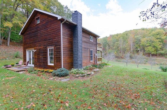 view of property exterior featuring french doors, a yard, and a chimney