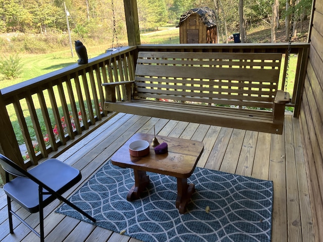 deck featuring a yard, a wooded view, a storage shed, and an outdoor structure