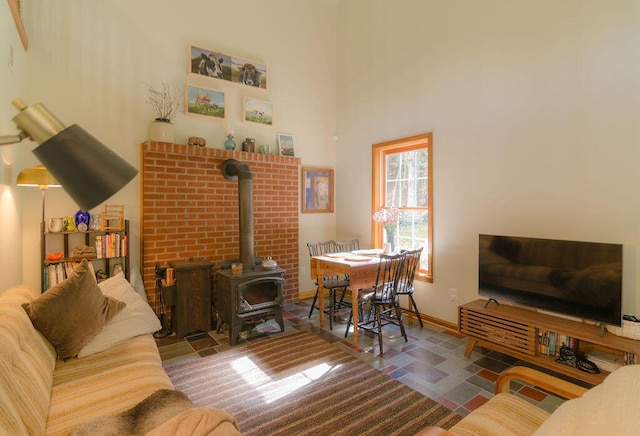 living room with a high ceiling, a wood stove, and baseboards