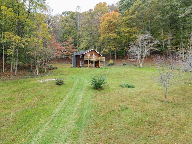 view of yard with an outbuilding, driveway, and a view of trees