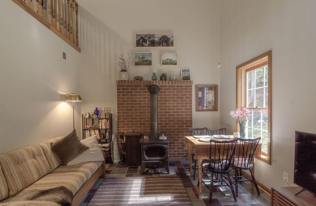 living room featuring visible vents, a towering ceiling, and a wood stove