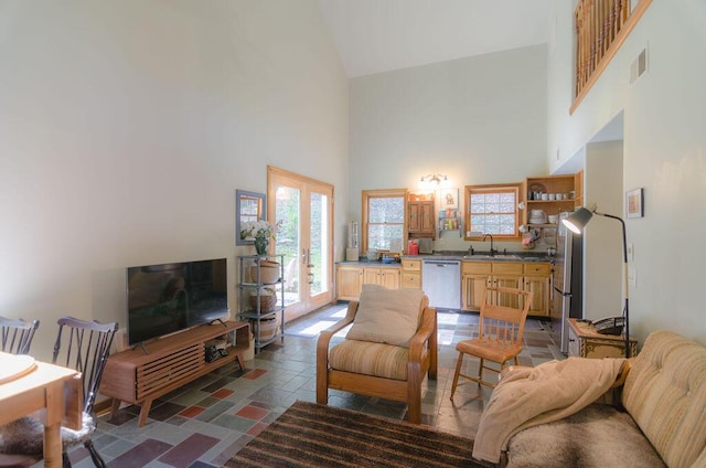 living room with french doors, a high ceiling, visible vents, and stone tile flooring