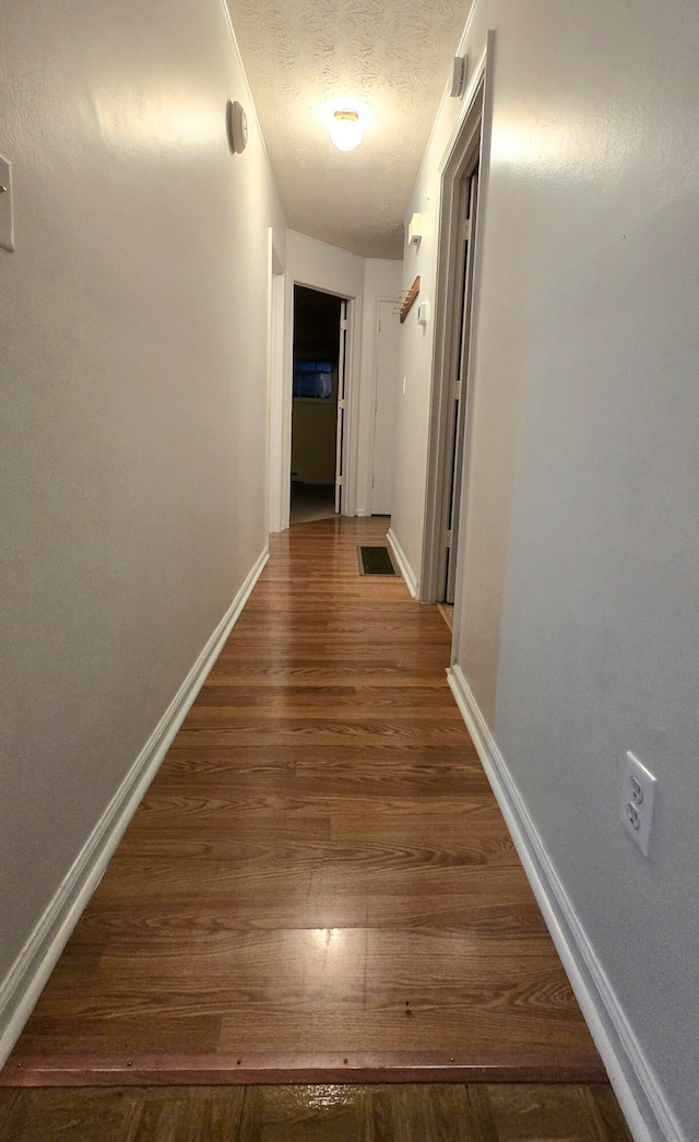 hall with dark hardwood / wood-style flooring and a textured ceiling