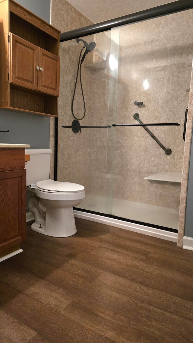 bathroom featuring walk in shower, toilet, vanity, and hardwood / wood-style flooring