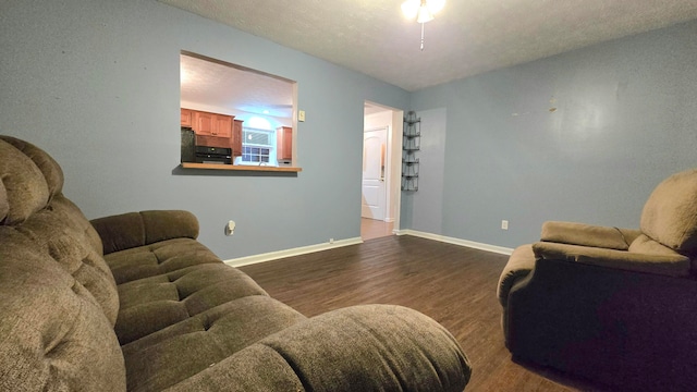 living room with a textured ceiling, dark hardwood / wood-style flooring, and ceiling fan