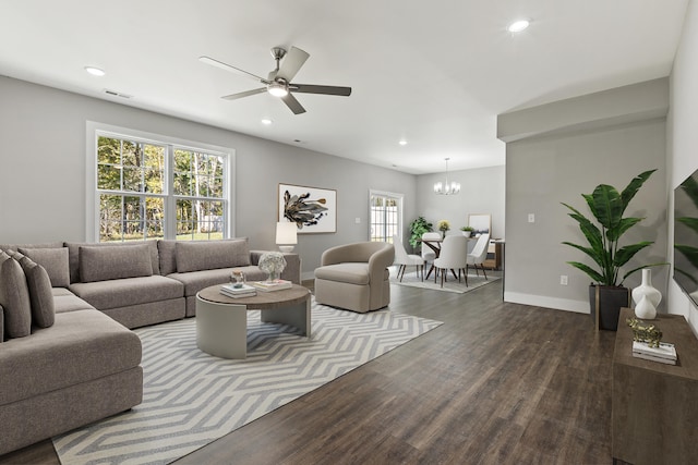 living room with dark wood-type flooring and ceiling fan with notable chandelier