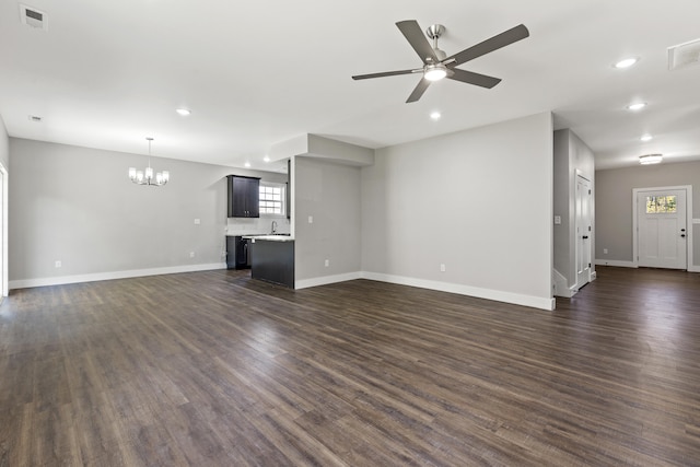 unfurnished living room with sink, dark hardwood / wood-style flooring, plenty of natural light, and ceiling fan with notable chandelier