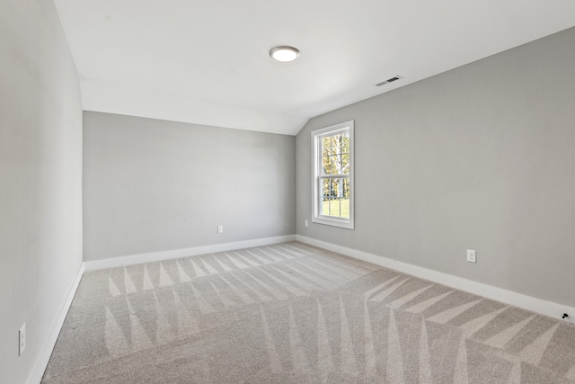 spare room featuring light carpet and lofted ceiling