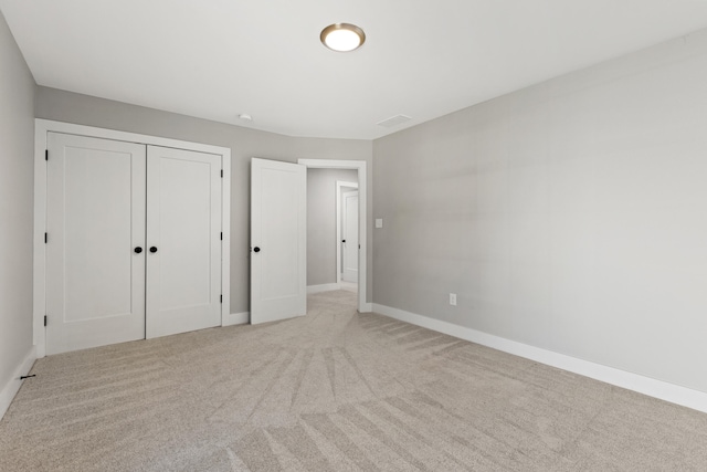 unfurnished bedroom with a closet and light colored carpet