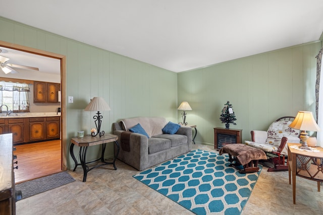 living room featuring ceiling fan, sink, and wood walls