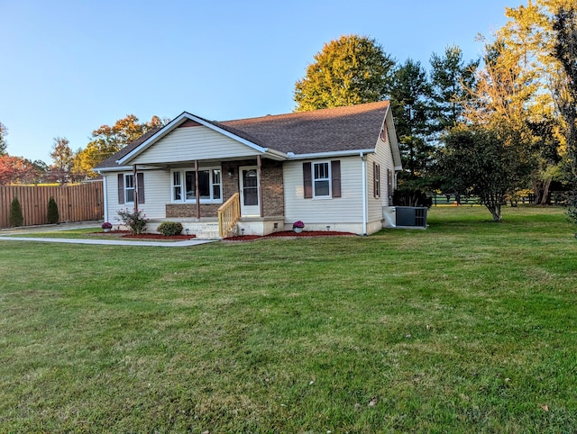 ranch-style house featuring covered porch, central AC, and a front lawn