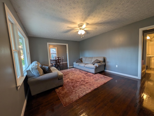 living room with ceiling fan, a textured ceiling, and dark hardwood / wood-style flooring