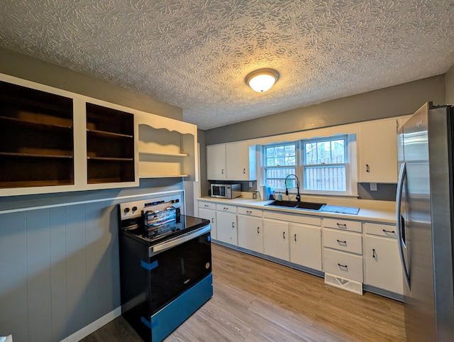 kitchen featuring white cabinets, appliances with stainless steel finishes, a textured ceiling, light hardwood / wood-style flooring, and sink