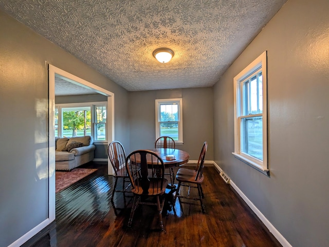 dining area with a textured ceiling and dark hardwood / wood-style flooring