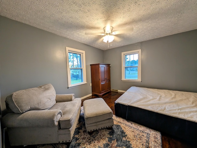 bedroom with ceiling fan, a textured ceiling, and dark hardwood / wood-style floors