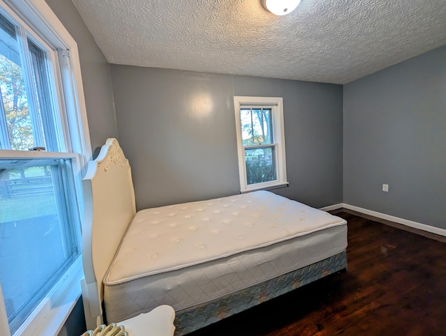 bedroom featuring a textured ceiling and dark hardwood / wood-style flooring