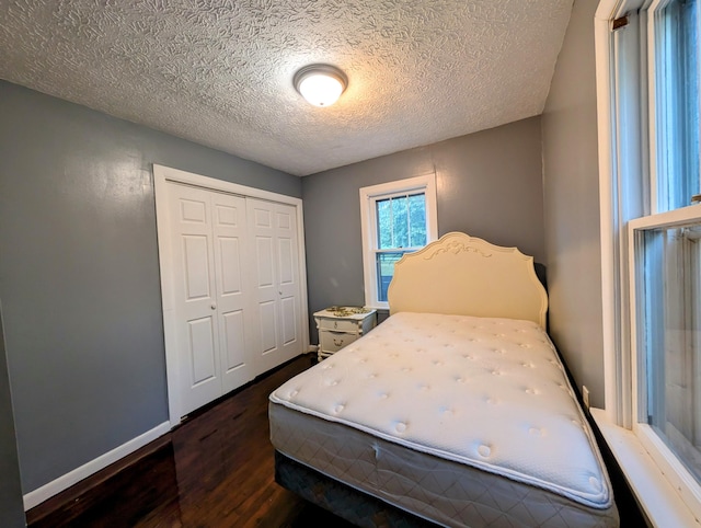 bedroom featuring a closet, a textured ceiling, and dark wood-type flooring