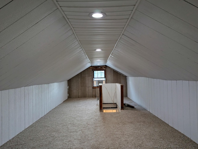 bonus room with wood walls, carpet, and vaulted ceiling