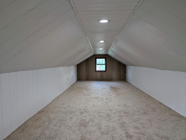 bonus room featuring light carpet, lofted ceiling, and wooden walls