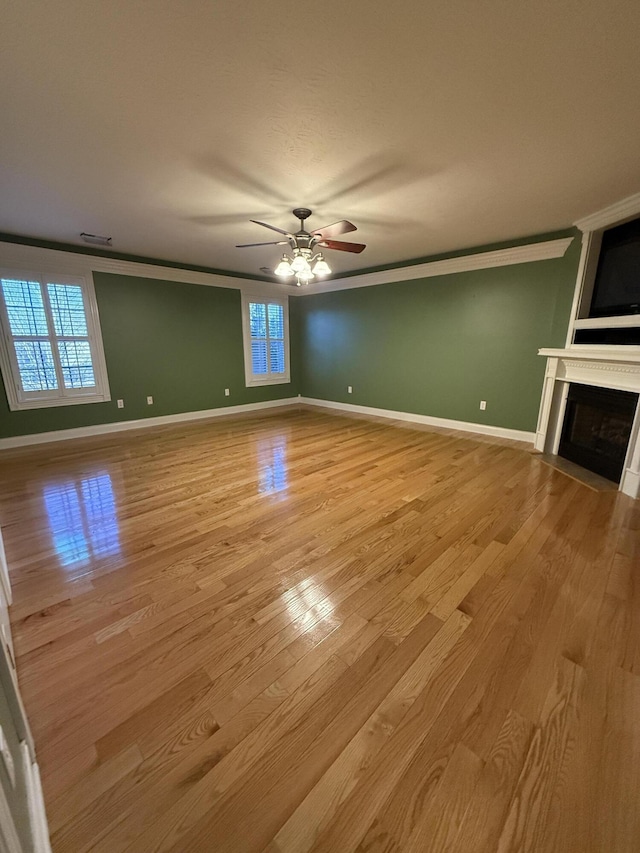 unfurnished living room with light wood-type flooring, ceiling fan, and ornamental molding