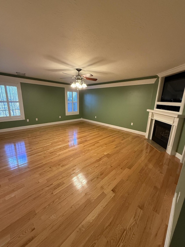 unfurnished living room with light hardwood / wood-style flooring, ceiling fan, and crown molding