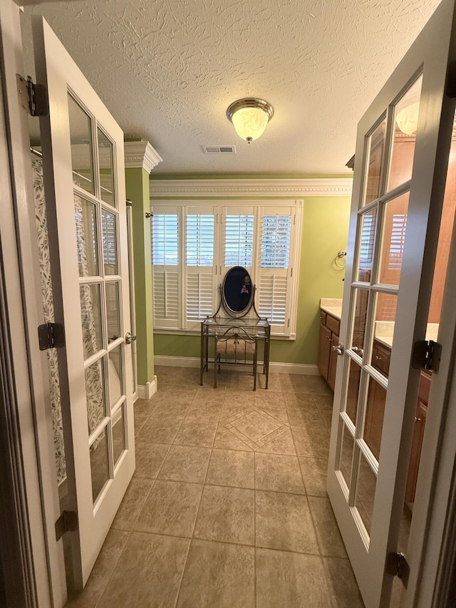 interior space featuring tile patterned floors, a textured ceiling, crown molding, and french doors