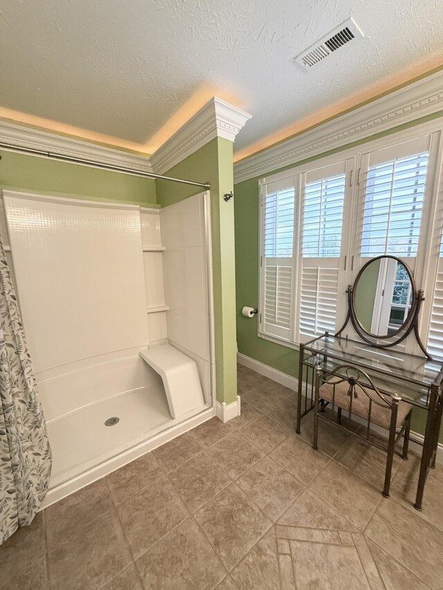 bathroom with a shower, ornamental molding, and a textured ceiling