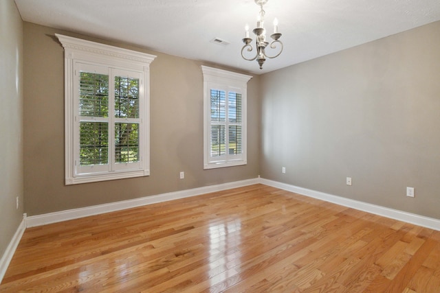 empty room featuring light hardwood / wood-style flooring and a notable chandelier